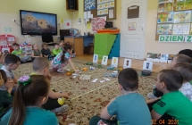 Pieciolatki z gr. V segreguja rozne odpady do oznaczonych z zasadami recyklingu pojemnikow.