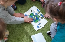 Dzieci w zespołach układają na dywanie puzzle - Ziemię