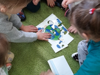 Dzieci w zespołach układają na dywanie puzzle - Ziemię