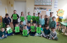 Dzieci stoją i trzymają w rękach litery ułożone w hasło Dzień Ziemi