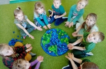 Dzieci z grupy VIII prezentują Ziemię ułożoną z zielonych i niebieskich nakrętek.