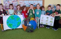 Dzieci z grupy VIII pozują z namalowaną Ziemią, plakatem i piłką - kulą ziemską.