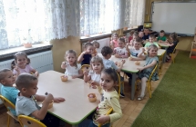 Dzieci siedza przy stolikach i trzymaja desery lodowe