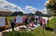 Przedszkolaki rysuja na tablicach oraz chodniku kolorowa kreda