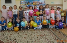 Usmiechniete pieciolatki pozuja grupowo z balonami.