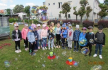 Wesole pieciolatki pozuja z bankami mydlanymi w ogrodzie.