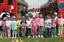 Pieciolatki z grupy V ze strazakami na tle wozow strazackich.