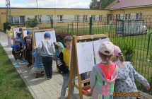 Pieciolatki podcza s rysowania kredkami na sztalugach.