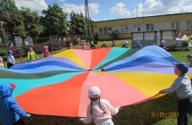 Dzieci z grupy V podczas zabawy z chusta animacyjna w ogrodzie przedszkolnym.