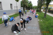 Dzieci piecioletnie z gr. V rysuja kreda na asfalcie.