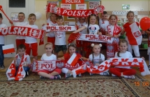 Radosne dzieci z gr. V prezentuja gadzety kibicow.
