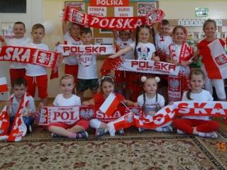 Radosne dzieci z gr. V prezentuja gadzety kibicow.