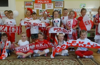 Usmiechniete dzieci z gr. V w bialo-czerwonych strojach.