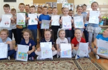 Usmiechniete dzieci z grupy V z rysunkami wykonanymi w ramach modulu Ksiazki dziecinstwa.