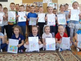 Usmiechniete dzieci z grupy V z rysunkami wykonanymi w ramach modulu Ksiazki dziecinstwa.
