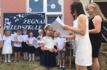 Pani dyrektor wrecza dziewczynce dyplom ukonczenia przedszkola.