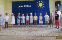 Dzieci piecioletnie z gr. V w kapeluszach i okularach spiewaja wakacyjna piosenke.