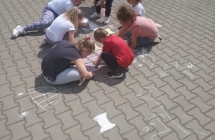 Dzieci rysuja kreda na kostce przed przedszkolem.