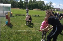 Dziewczynka w rozowej kurtce celuje woda z weza do tarczy