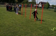 Dzieci ustawione w pociag, chlopiec w czarnej kurtce biegnie slalomem miedzy slupkami.