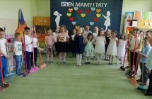 dzieci ustawione w polkolu, po bokach chlopcy trzymaja szczotki  - rekwizyty do tanca.