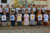 Usmiechniete dzieci z gr. VII z literami tworzacymi haslo Mysle, wiec nie smiece