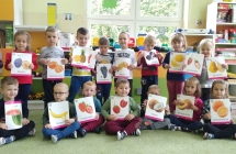 Dzieci trzymaja ilustacje przedstawiajace owoce