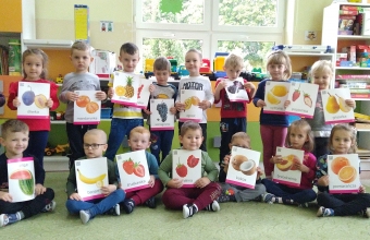 Dzieci trzymaja ilustacje przedstawiajace owoce