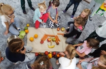 Dziewczynki ukladaja ludzika z warzyw i owocow