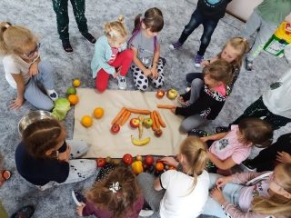 Dziewczynki ukladaja ludzika z warzyw i owocow