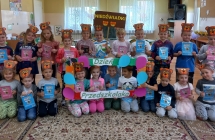 Radosne przedszkolaki z gr. VII pozuja z napisem Dzien Przedszkolaka i upominkami.