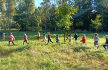 Dzieci biegna slalomem miedzy drzewami.