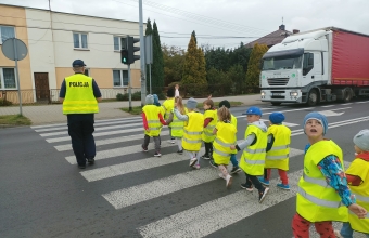 Dzieci w towarzystie policjanta przechodza przez jezdnie