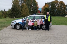 Dzieci z grupy IV stoja przed radiowozem w towarzystwie policjanta