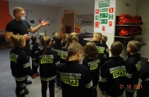 Strażak objaśnia dzieciom rodzaje i znaczenie znaków ewakuacyjnych. 