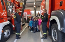 Sześciolatki słuchają objaśnień strażaków dot. wyposażenia samochodów strażackich. 