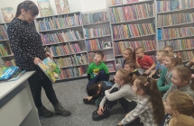 Dzieci z gr. VII oglądają książkę prezentowaną przez dyr. biblioteki. 