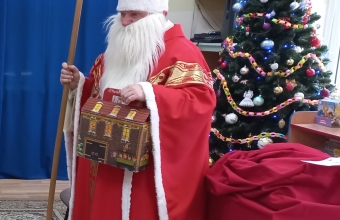 Mikolaj z prezentami przy choince.