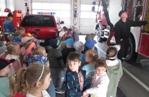 dzieci ogladaja wozy strazackie i sprzet uzywany w pracy strazaka