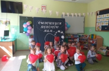 dzieci klecza z czerwonymi balonami w rekach