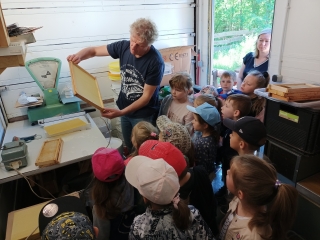 dzieci przygladaja sie pracy pszczelarza