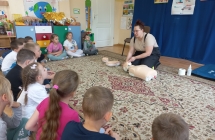 Pani strazak demonstruje dzieciom czynnosci ratownicze.