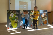 Chlopcy umieszczaja zdjecia odpadow na planszach z wizerunkami koszy.