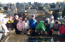 dzieci stawiaja znicze na grobie