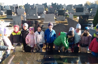 dzieci stawiaja znicze na grobie