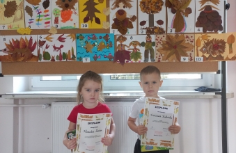 Klaudia i Franio z gr. I z dyplomami i nagrodami na tle prac konkursowych.