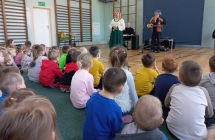 Muzycy grający dla dzieci w  sali szkolnej 