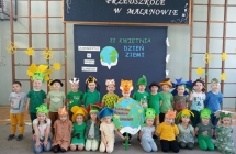 Kilkanaścioro dzieci na tle baneru w szkolnym holu 