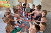 Dzieci z wyciętymi sercami z papieru położonymi na dłoniach 