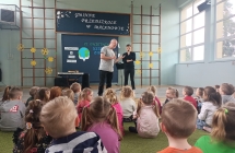 Dzieci słuchające dwójki mężczyzn prezentujących instrumenty muzyczne 